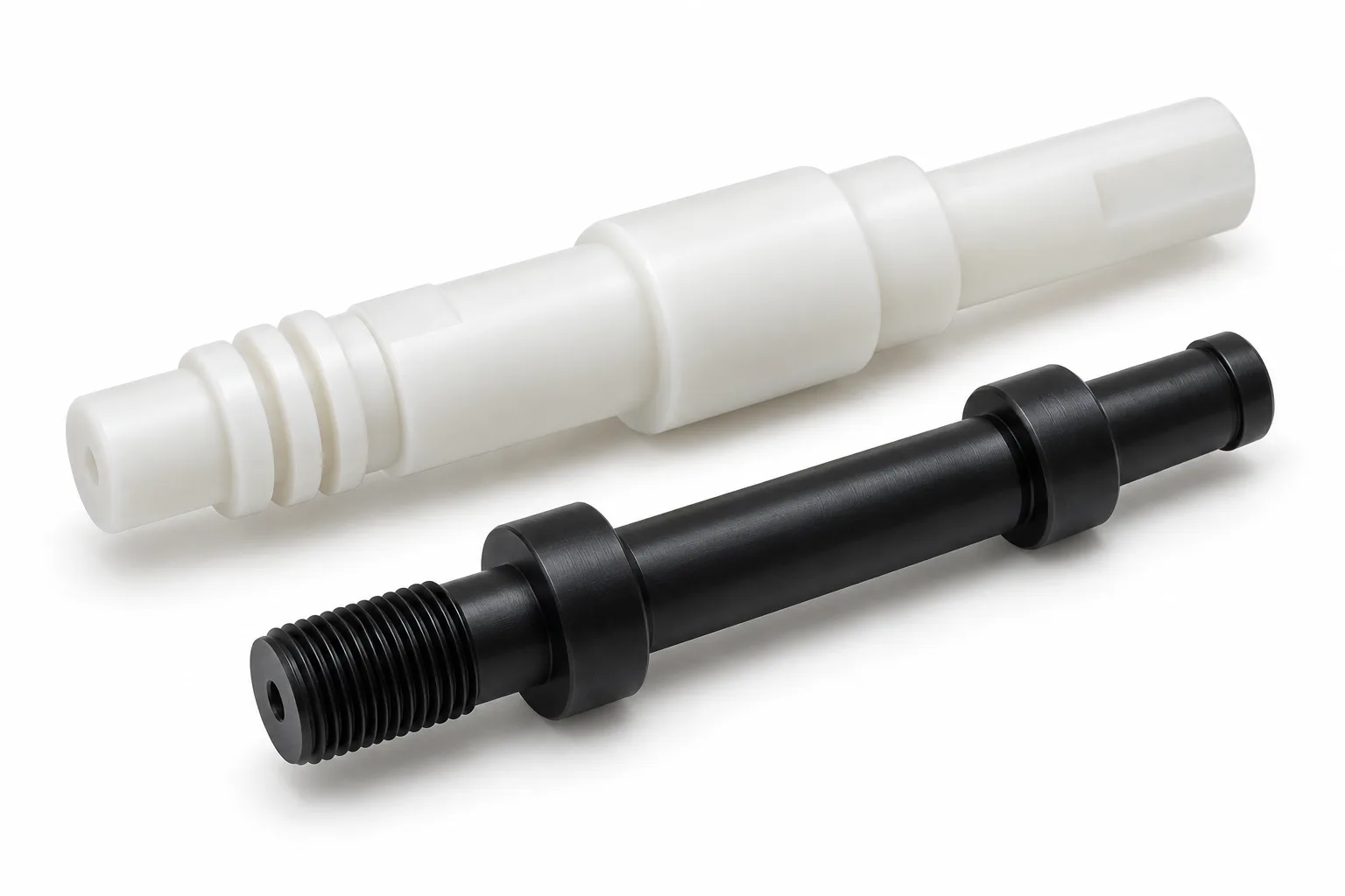 Natural white stepped acetal shaft and black threaded acetal shaft on a white studio background
