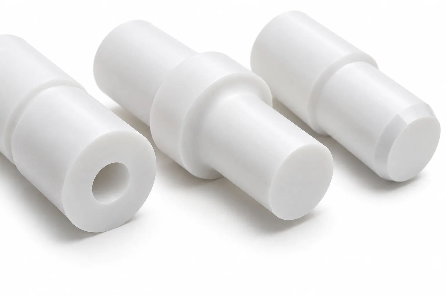 White PTFE shaft ends showing a drilled bore, rounded shoulder and fine turned surfaces