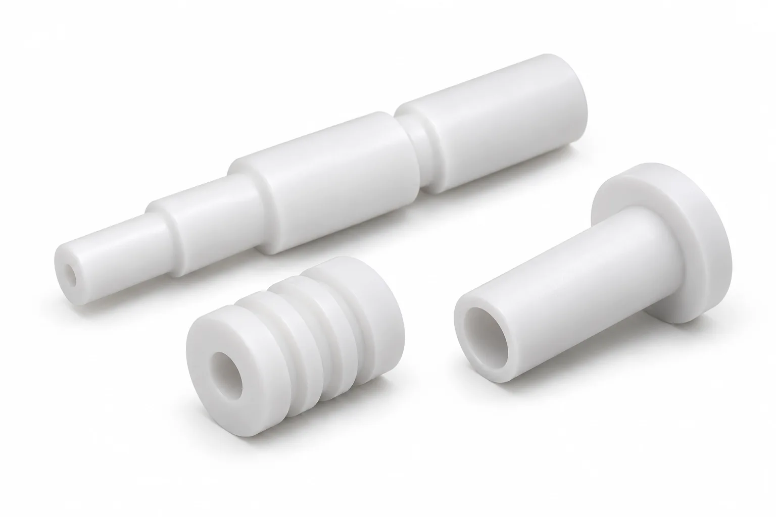 White finished PTFE shafts with stepped, grooved and hollow machined features on a white background